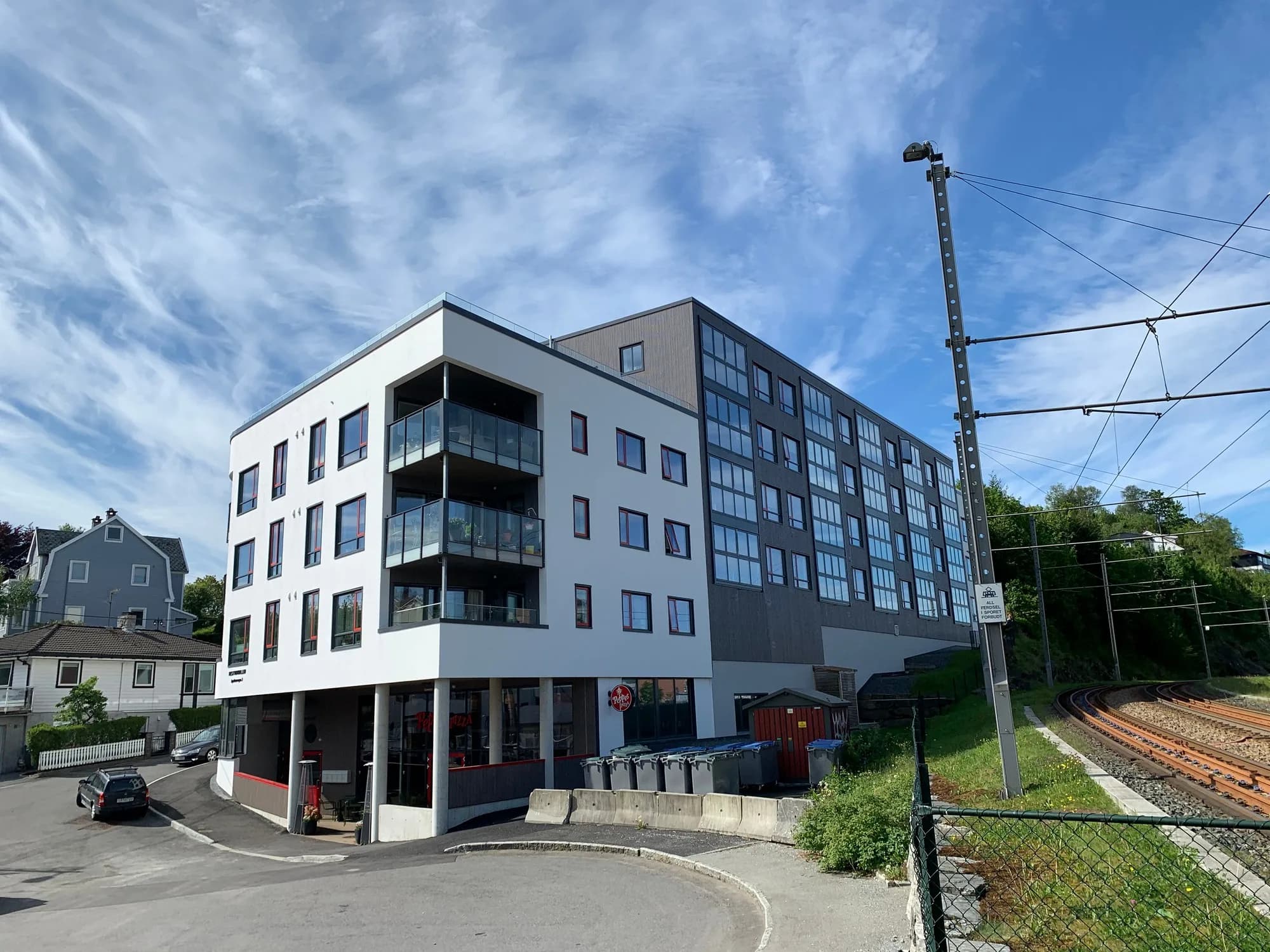 Hvitt og grått leilighetsbygg ved jernbanesporet