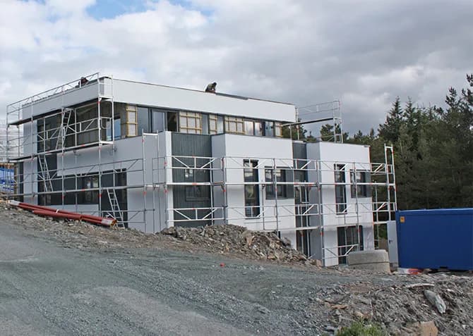 Hvitt bygg under arbeid, med stillas